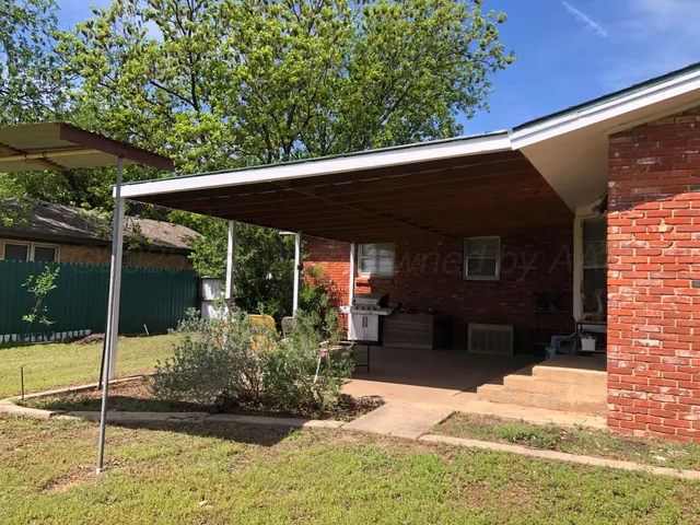 a view of a patio with a table and chairs and a barbeque