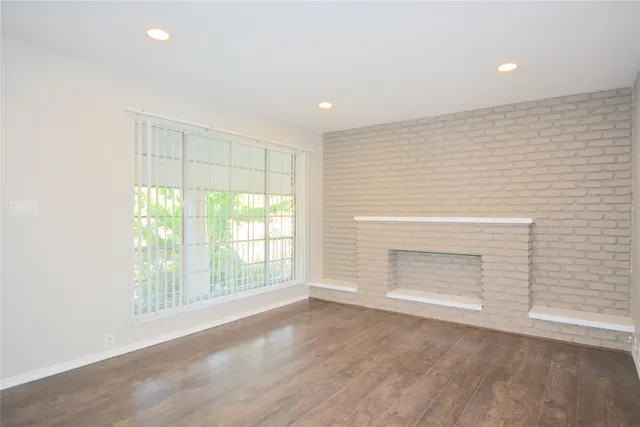 an empty room with windows and fireplace