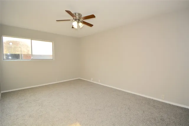 an empty room with a window and a fan