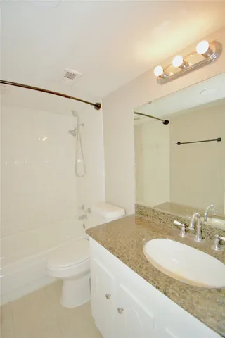a bathroom with a granite countertop sink a toilet and shower