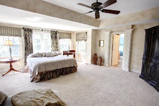 24145 West Milton Road Hawthorn Woods, IL 60047 - Photo 11 of 16 a spacious bedroom with a bed a ceiling fan and a large window