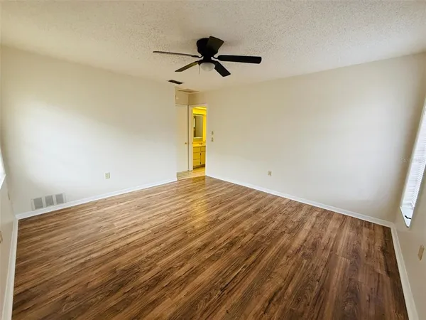 a view of empty room with wooden floor and fan