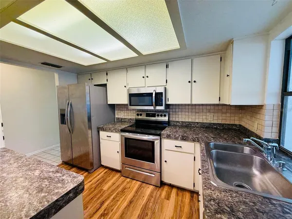 a kitchen with granite countertop kitchen island stainless steel appliances a sink stove and cabinets