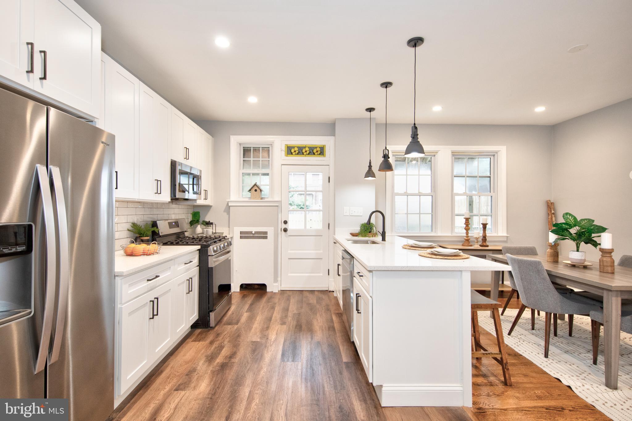 416 Dunkirk Road Baltimore, MD 21212 - Photo 10 of 33 a kitchen with stainless steel appliances a stove a sink dishwasher a refrigerator white cabinets and wooden floor next to a window