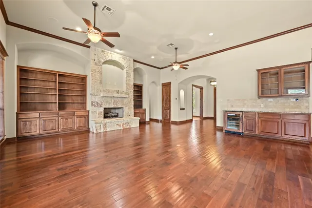 a view of an empty room with wooden floor fireplace and a window