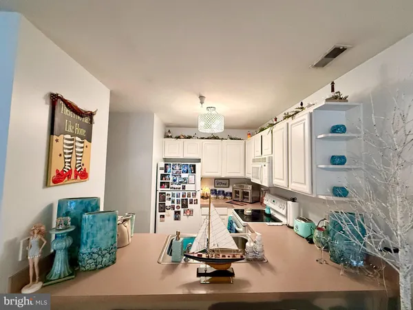 a room with lots of white furniture and potted plants