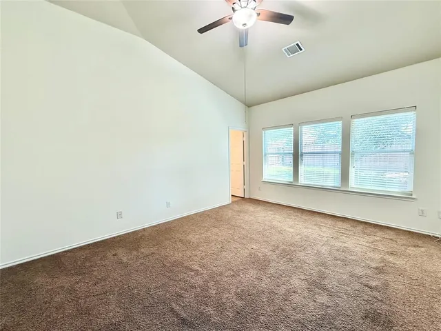 an empty room with a chandelier fan and windows