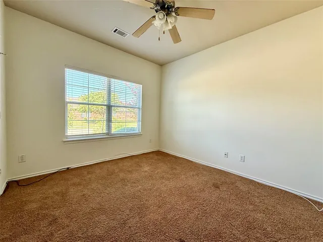 an empty room with a ceiling fan and window