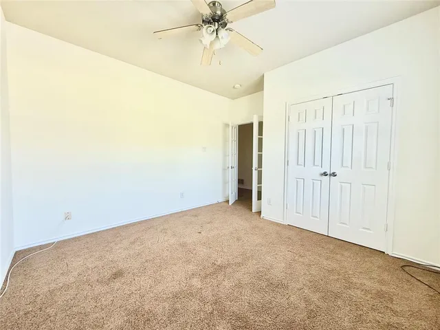 an empty room with a ceiling fan and window