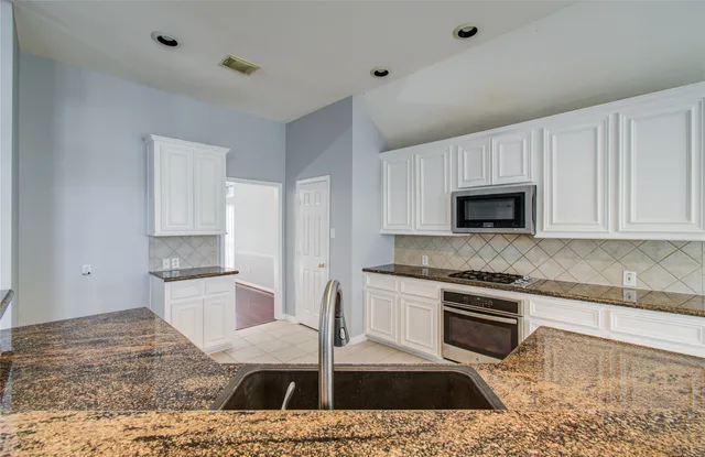 a kitchen with white cabinets and stainless steel appliances