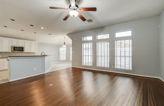 a view of an empty room with wooden floor and a fireplace