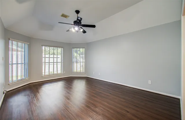 an empty room with wooden floor and windows
