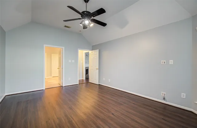 an empty room with wooden floor ceiling fan and window