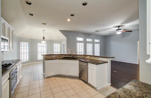 a kitchen with granite countertop a sink and white cabinets