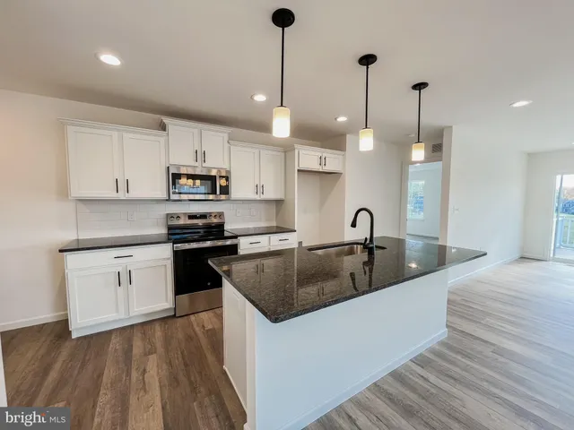 a kitchen with kitchen island a sink stainless steel appliances and cabinets