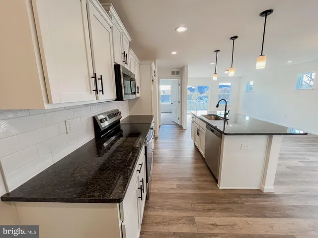 a kitchen with stainless steel appliances granite countertop a sink a stove and a wooden floors