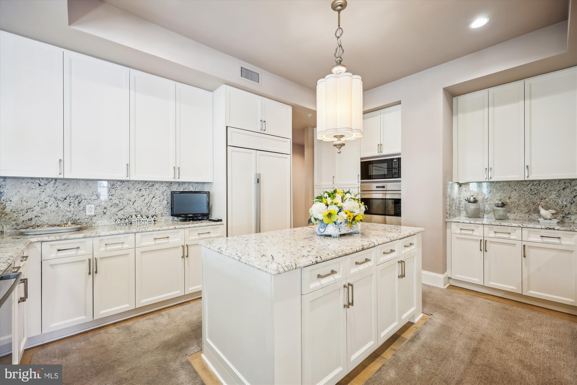 8121 River Road, Unit 451 Bethesda, MD 20817 - Photo 34 of 94 a kitchen with kitchen island granite countertop white cabinets white appliances a sink and a chandelier