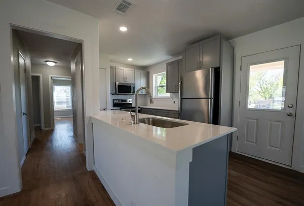 a kitchen with sink a refrigerator and wooden floor