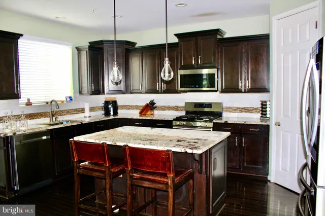 a kitchen with stainless steel appliances granite countertop a stove refrigerator sink and cabinets