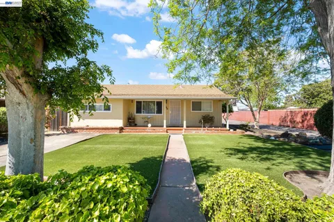 a front view of a house with a garden and trees