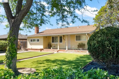 a front view of a house with a garden and trees