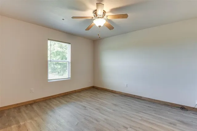 an empty room with windows and fan