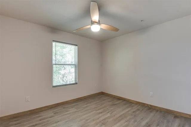 an empty room with wooden floor chandelier and windows