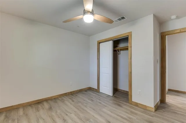 an empty room with wooden floor and a ceiling fan