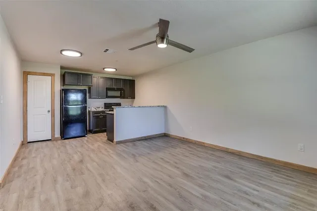 a view of kitchen with stainless steel appliances wooden floor and large window