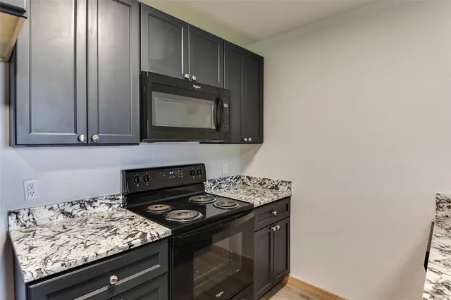 a kitchen with granite countertop cabinets stove top oven and microwave
