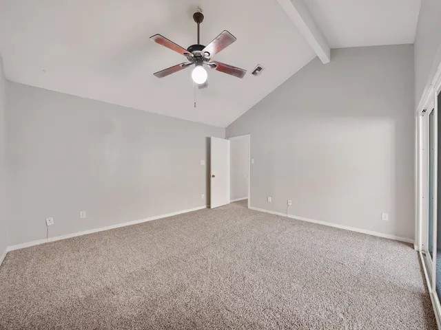 a view of an empty room with a chandelier fan
