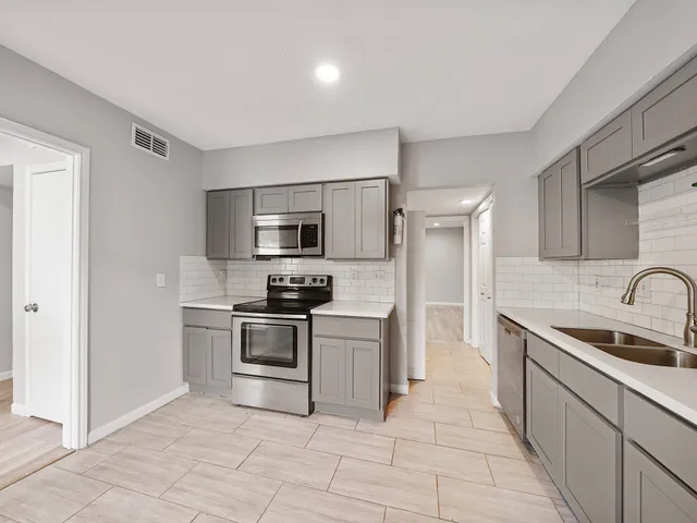 a kitchen with stainless steel appliances granite countertop a sink dishwasher stove top oven and refrigerator