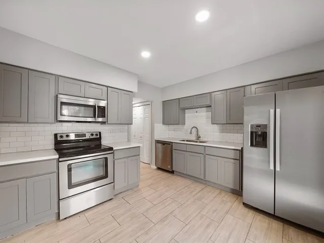 a kitchen with stainless steel appliances granite countertop a stove a sink and a refrigerator