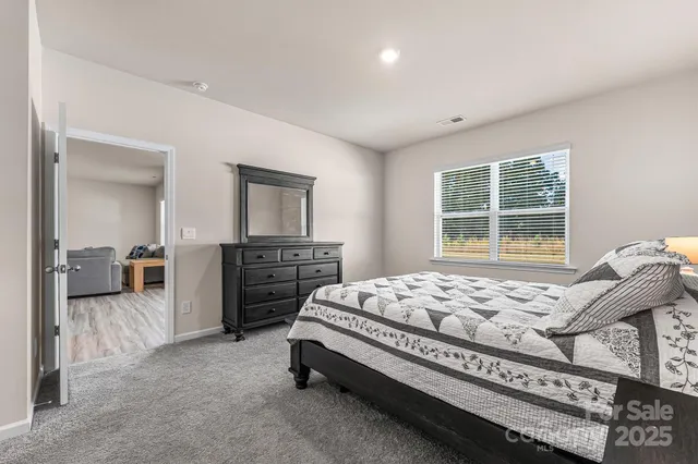 a bed sitting in a spacious bedroom next to a window