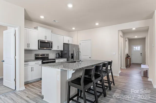 a kitchen with stainless steel appliances granite countertop a table chairs microwave and sink