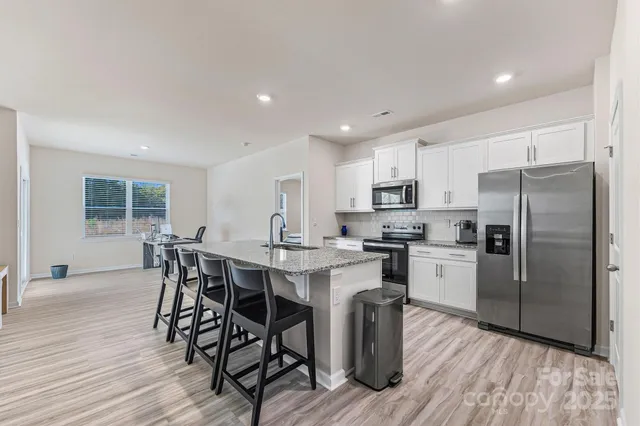 a kitchen with stainless steel appliances a dining table chairs stove refrigerator and microwave