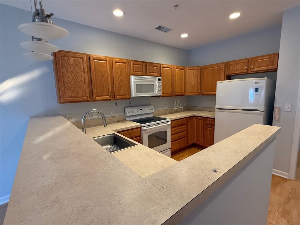 107 Clocktower Drive, Unit 207 Waltham, MA 02452 - Photo 2 of 18 a kitchen that has a microwave a sink and a stove in it