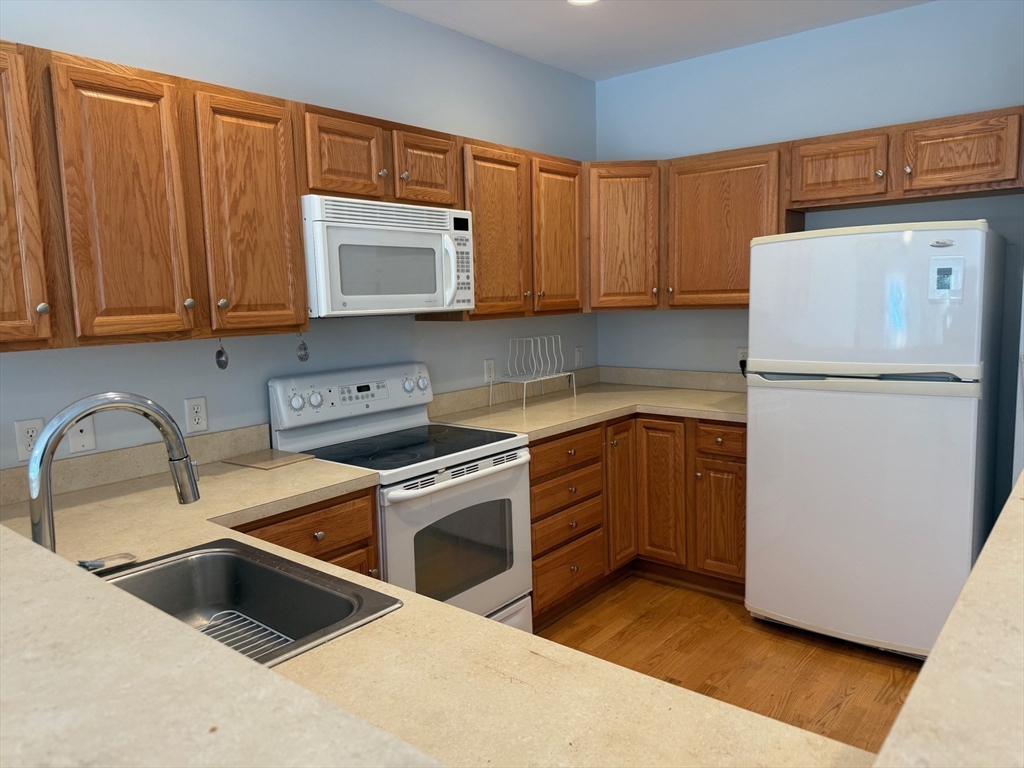 107 Clocktower Drive, Unit 207 Waltham, MA 02452 - Photo 3 of 18 a kitchen with a refrigerator sink and cabinets
