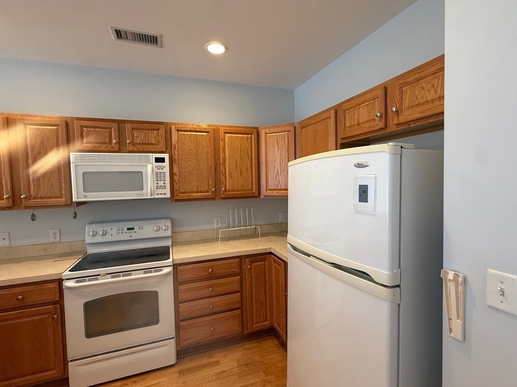 107 Clocktower Drive, Unit 207 Waltham, MA 02452 - Photo 5 of 18 a white refrigerator freezer and a stove sitting inside of a kitchen