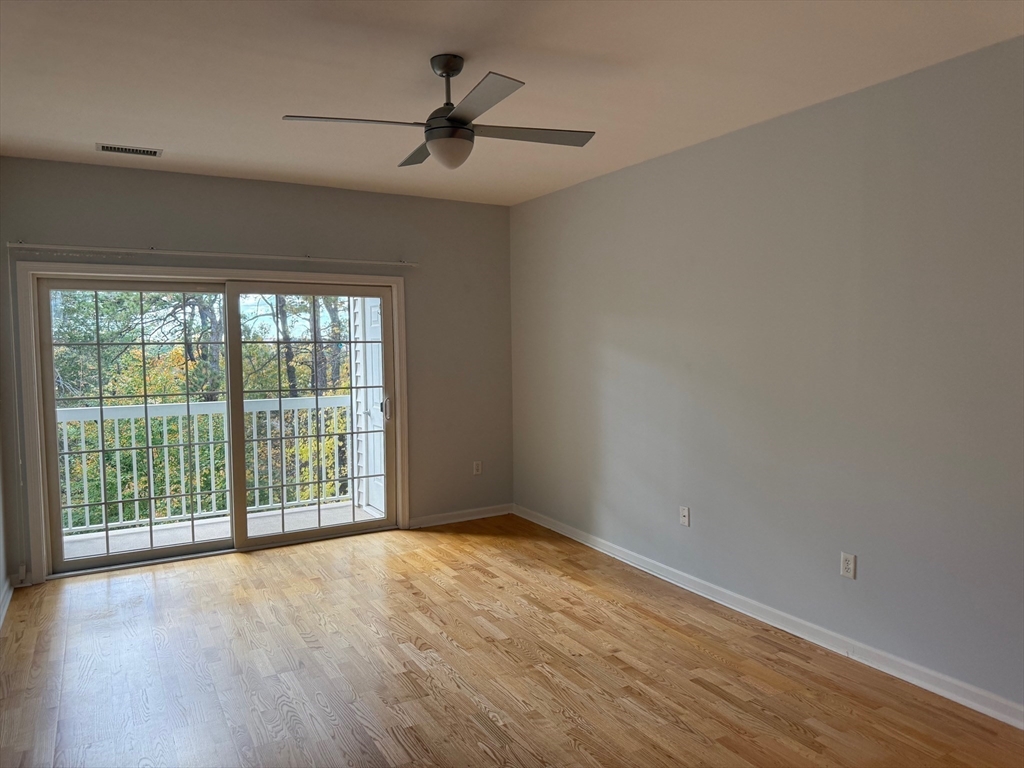107 Clocktower Drive, Unit 207 Waltham, MA 02452 - Photo 7 of 18 a view of an empty room with a window and wooden floor