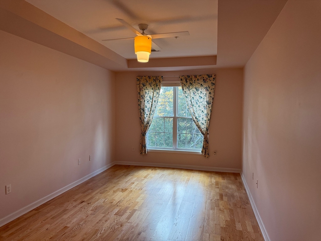 107 Clocktower Drive, Unit 207 Waltham, MA 02452 - Photo 10 of 18 an empty room with wooden floor and windows