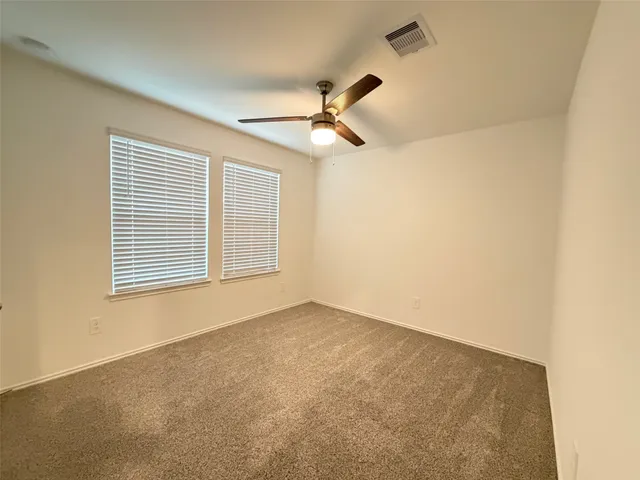 an empty room with a ceiling fan and a window