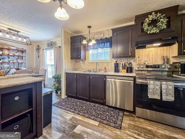 a kitchen with stainless steel appliances kitchen island granite countertop a sink stove and cabinets