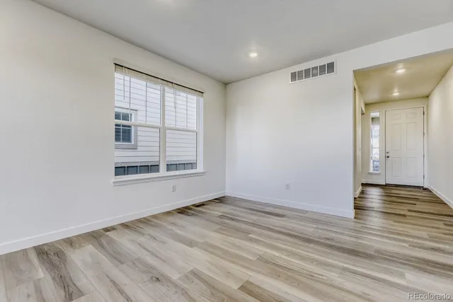 a view of an empty room with wooden floor and a window