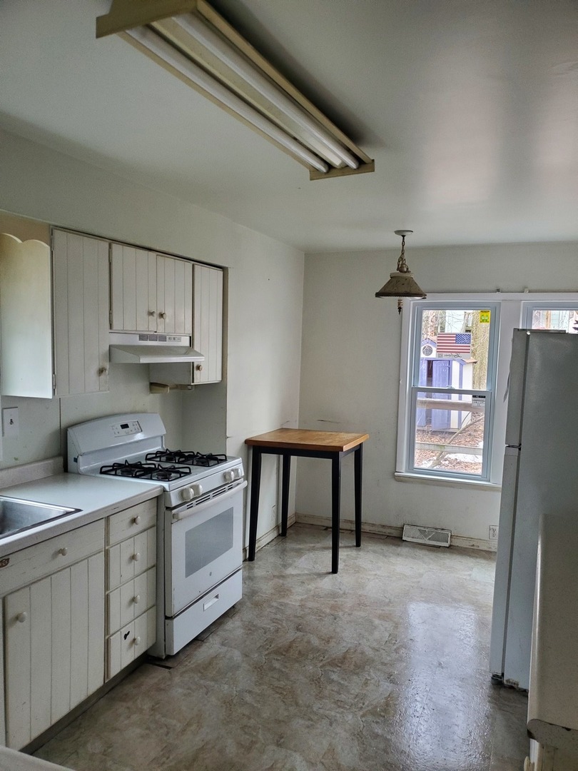 136 John Street DeKalb, IL 60115 - Photo 7 of 25 a kitchen with stainless steel appliances white cabinets and a refrigerator
