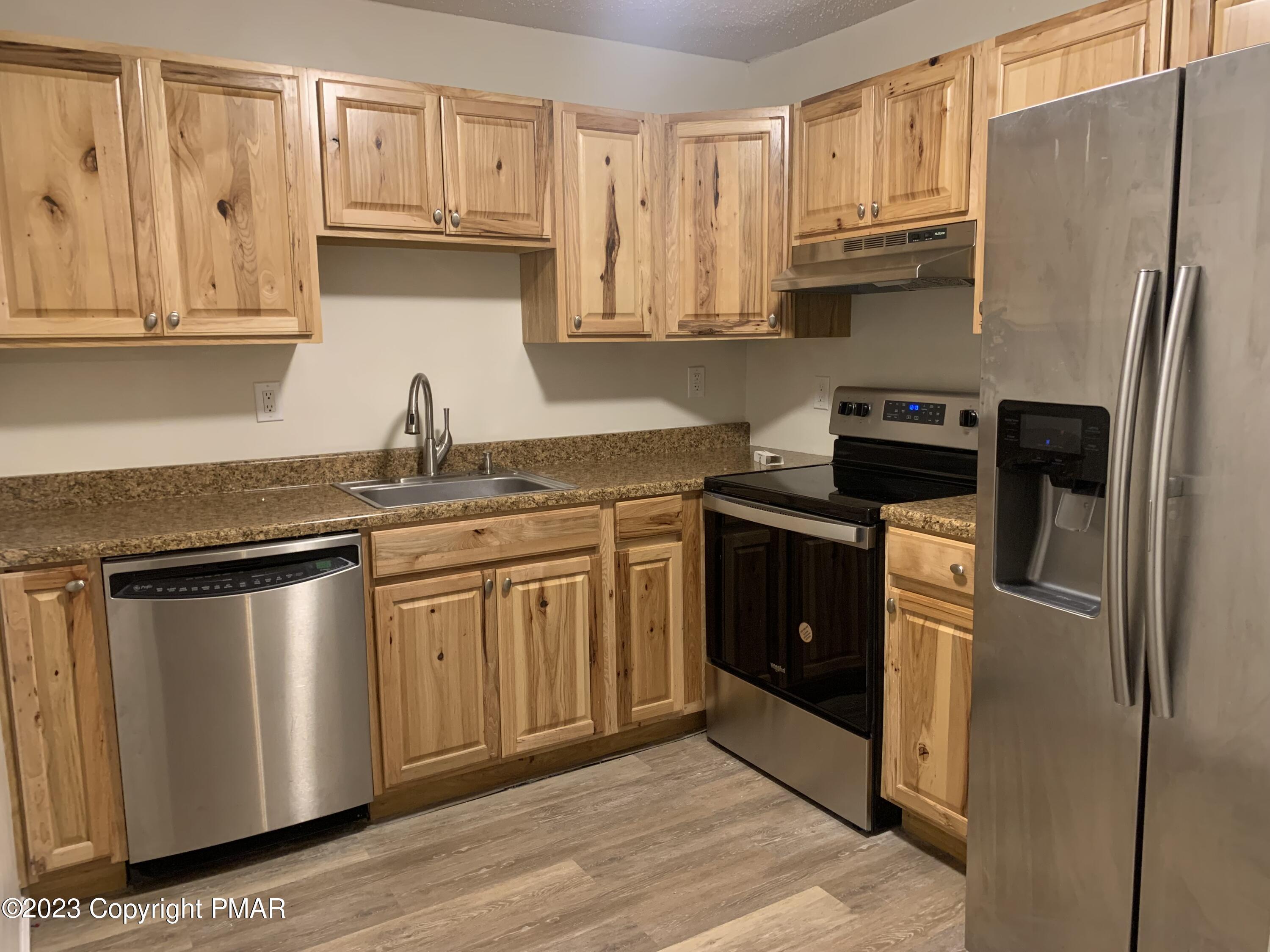 130 View Court, Unit 103 Mount Pocono, PA 18344 - Photo 2 of 11 a kitchen with stainless steel appliances granite countertop a refrigerator sink and cabinets