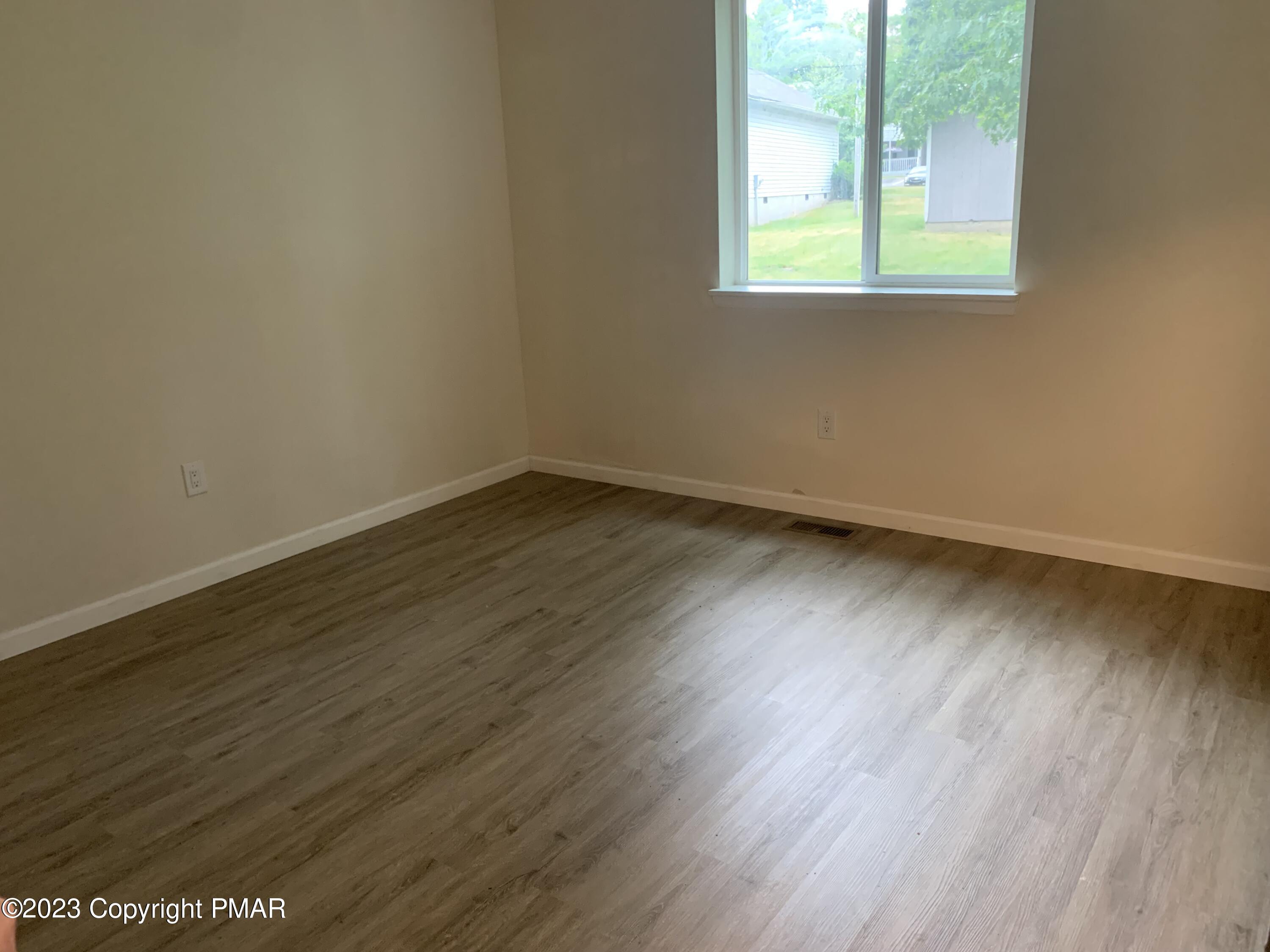 130 View Court, Unit 103 Mount Pocono, PA 18344 - Photo 6 of 11 an empty room with wooden floor and windows