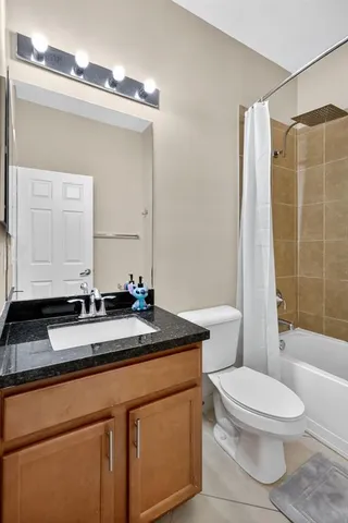 a bathroom with a granite countertop sink a toilet a mirror and shower