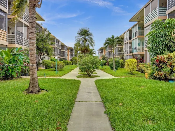 a view of a white house with a yard and potted plants