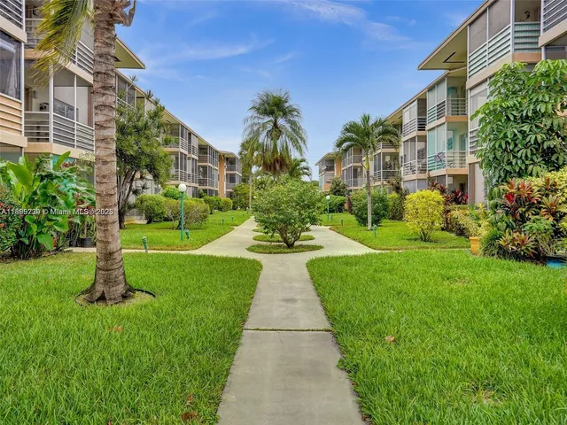 a view of a white house with a yard and potted plants